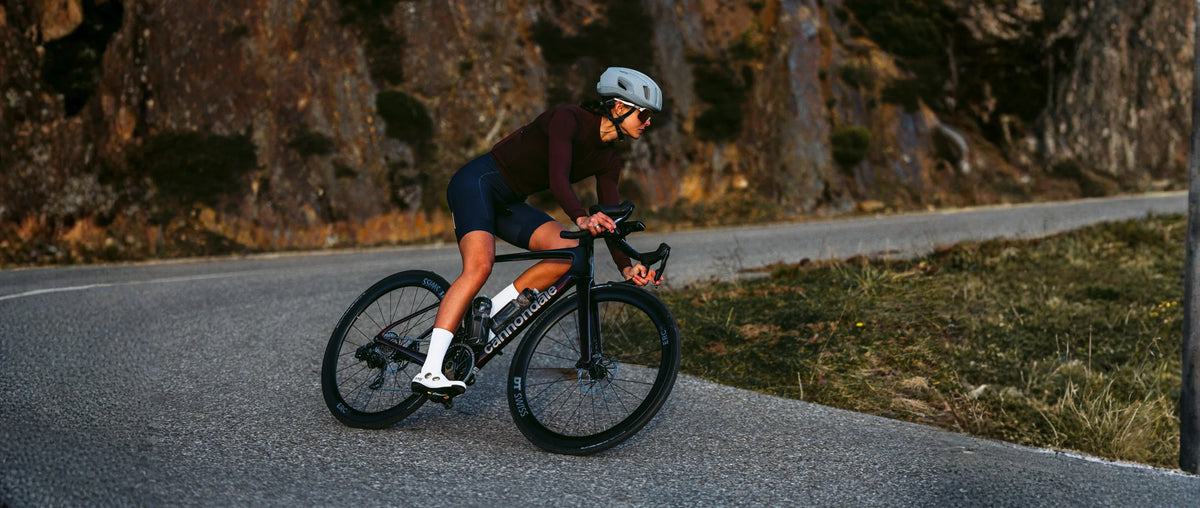 Ciclista en bicicleta de ruta Cannondale de carbono tomando una curva en carretera