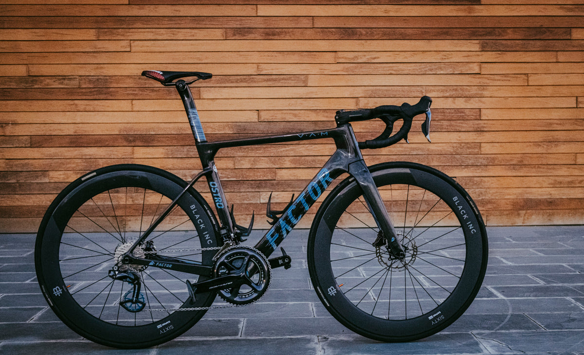 Bicicleta de ruta Factor Ostro VAM de carbono frente a una pared de madera